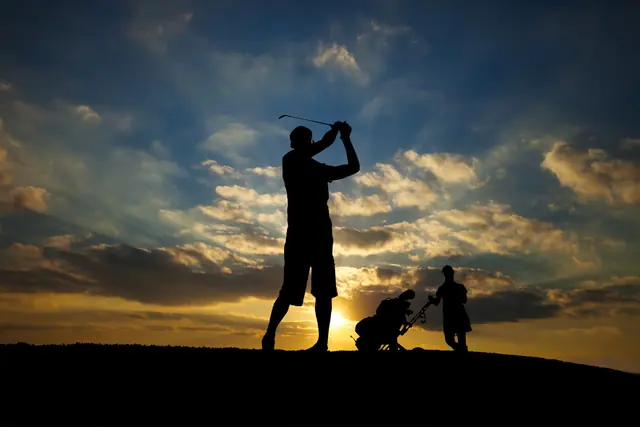 Golfer silhouetted against a golden sunset