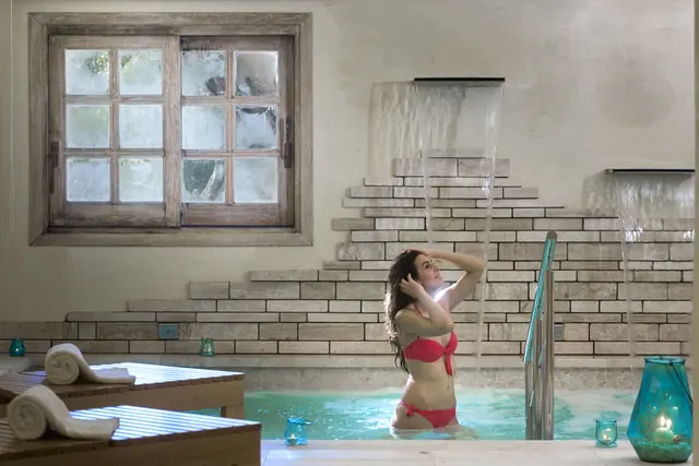 Guest enjoying a waterfall shower in a stone spa