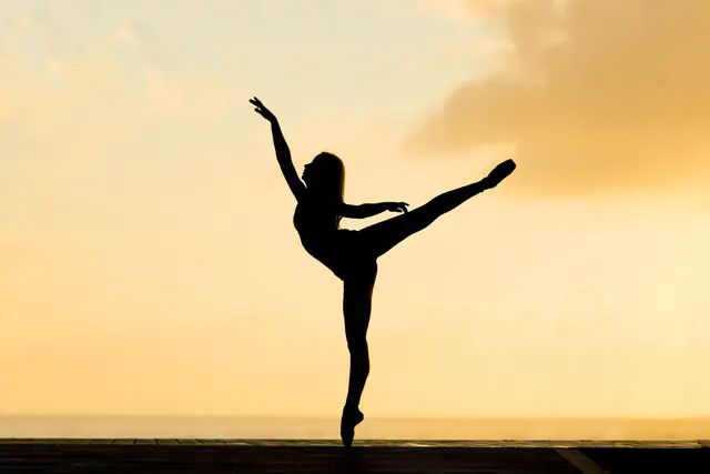 Ballerina in controluce contro un cielo dorato