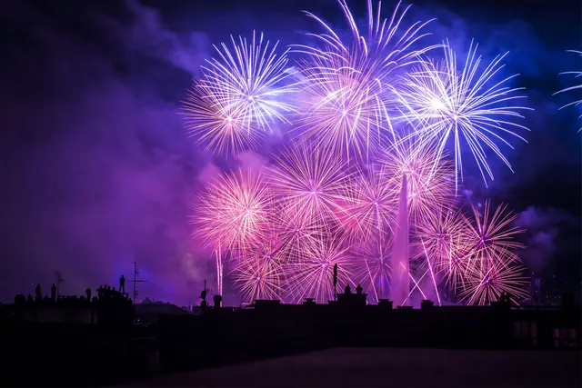 Fuochi d’artificio viola e rosa sopra lo skyline di notte