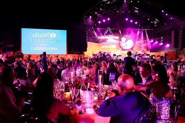 Cena di gala con un grande palco illuminato e una folla di ospiti