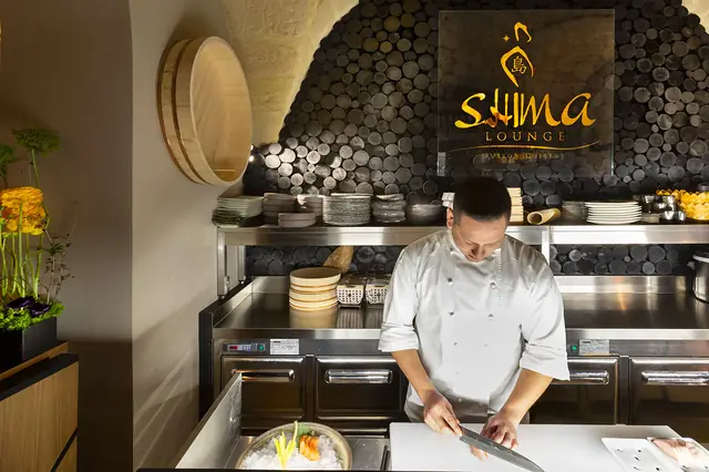 Chef che taglia il pesce al bancone del sushi